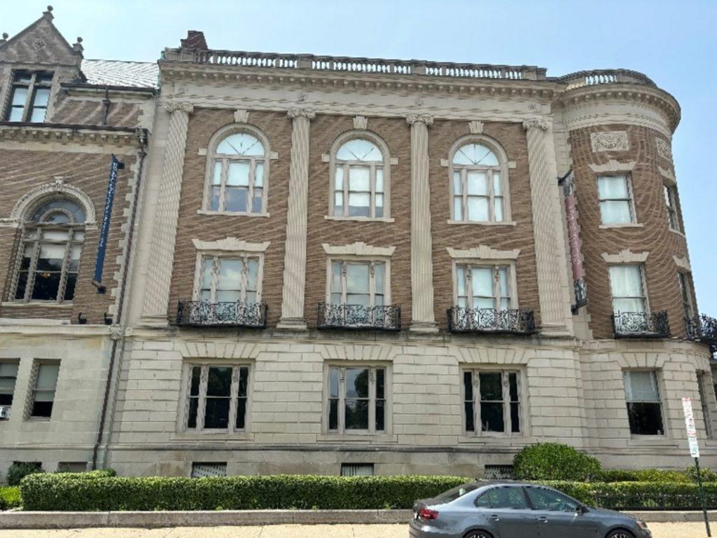 A modern photo of the western side of the Massachusetts Historical Building, with a stone exterior on the ground floor and brick exterior for upper floors. It is decorated with pilasters, windows, and balconettes.