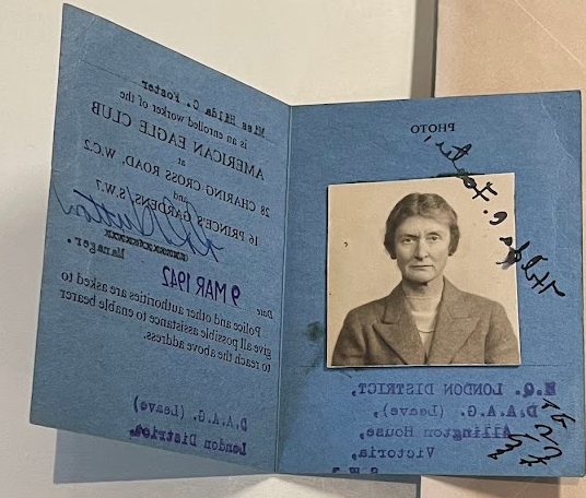 Color photograph of the inside of the Worker's Pass from the previous image with a black and white photograph on the left hand side of an older white woman with dark hair pulled back, she wears a dark jacket and a light shirt or dress. On the right it reads "American Eagle Club" and in a blue stamp, "9 MAR 1942."